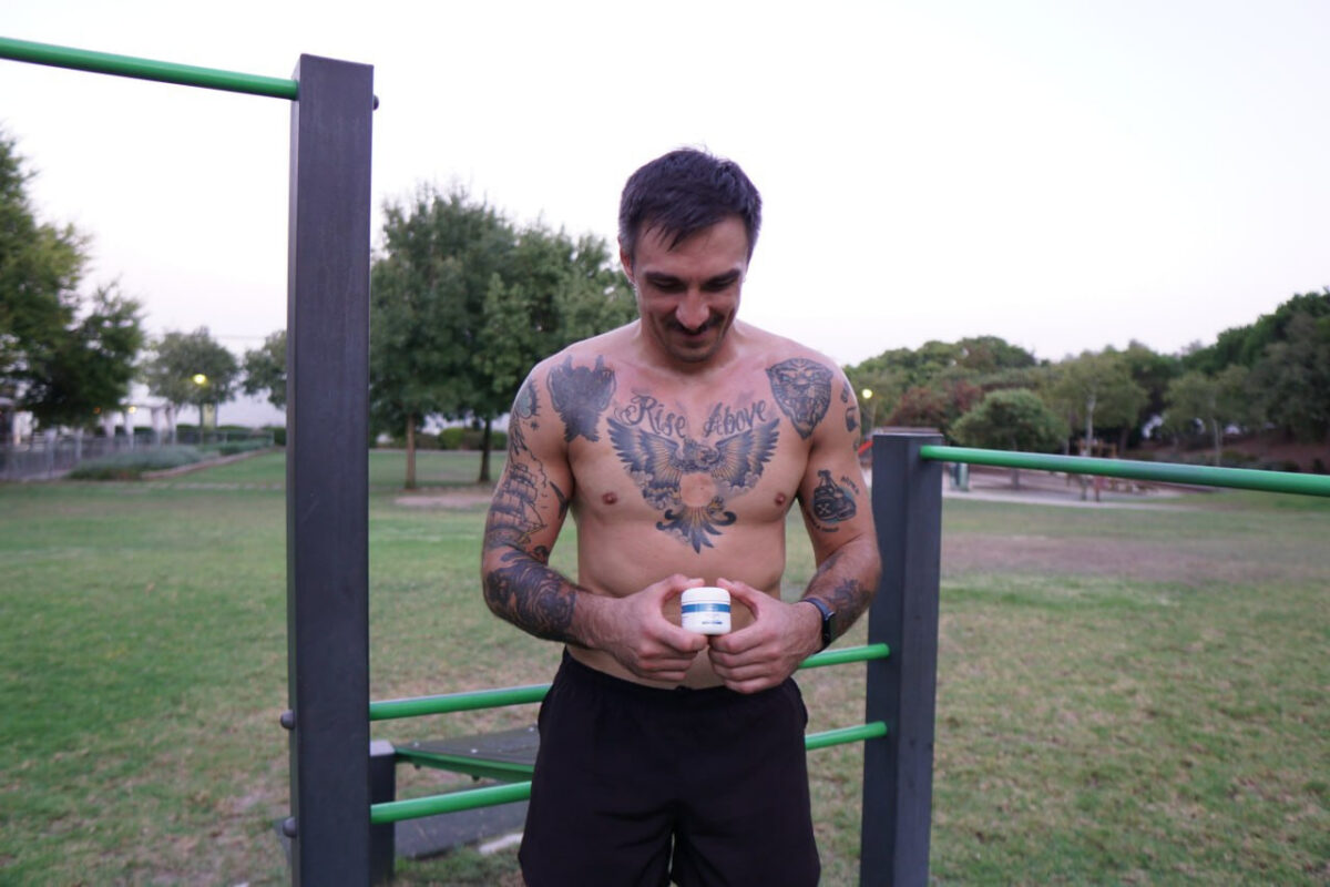 Athletic man holding CBDNorth CBD Body Balm jar at outdoor workout park – buy CBD pain cream Canada